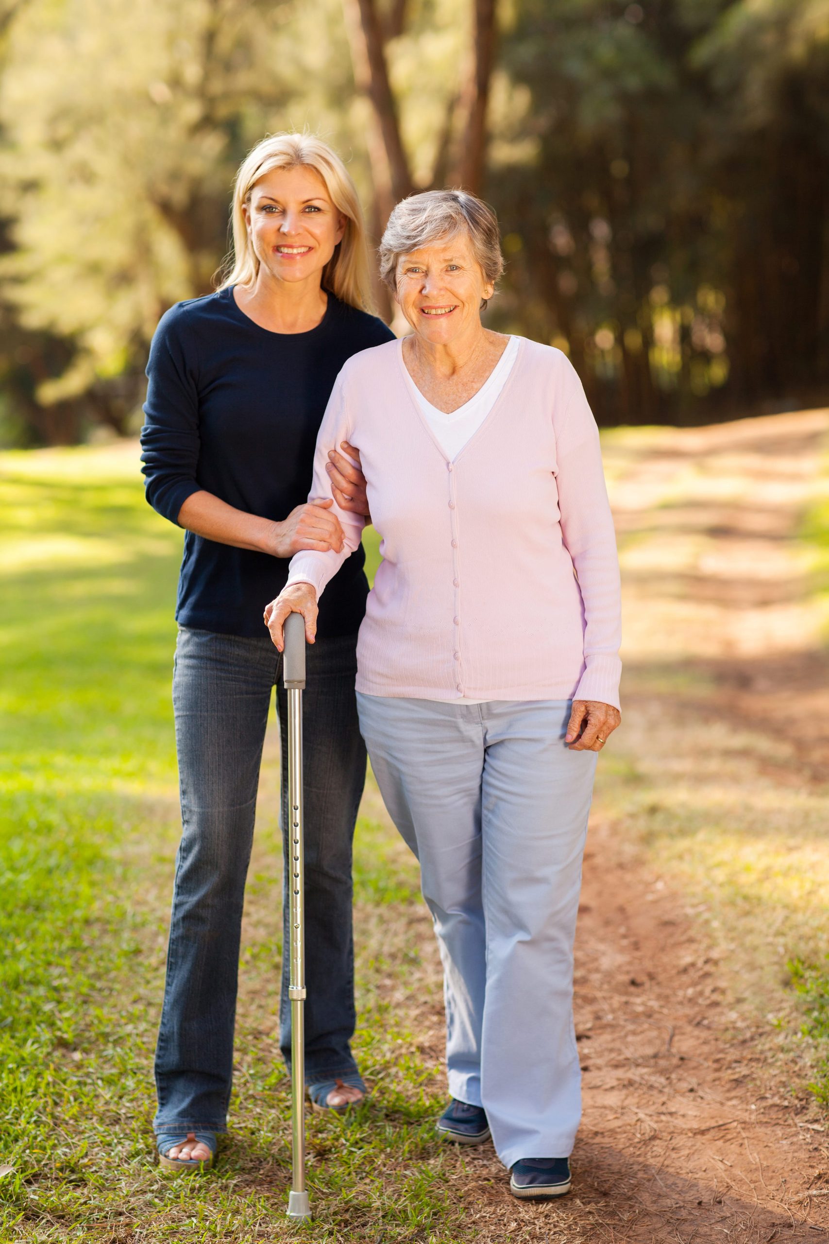 mujer joven acompañando a adulto mayor con bastón en caminata