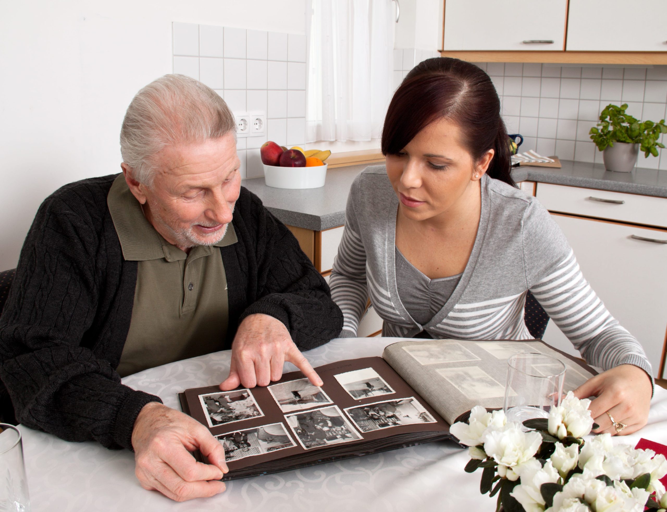 Adulto mayor mirando un album de fotos junto a mujer joven
