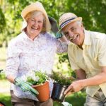 pareja mayor sonriendo mientras trabajan en el jardín