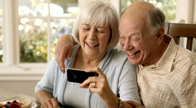 pareja de adulto mayores sonriendo frente a un teléfono celular