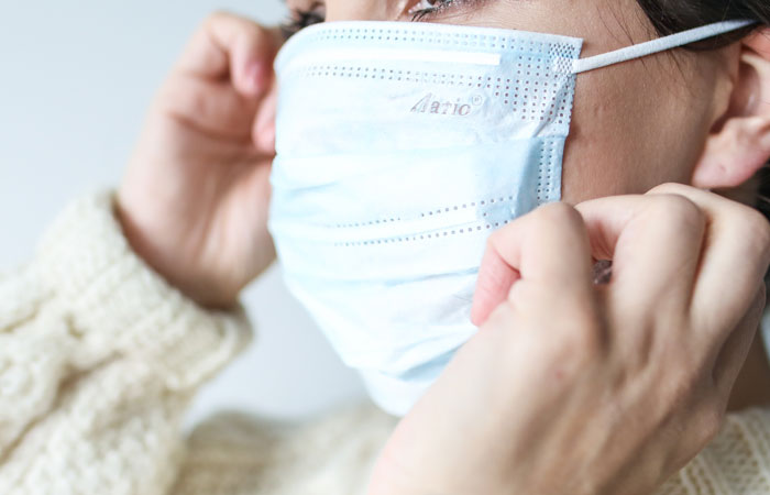 mujer colocándose una mascarilla quirúrgica