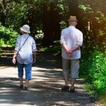 Pareja mayor caminando por un sendero rodeado de plantas