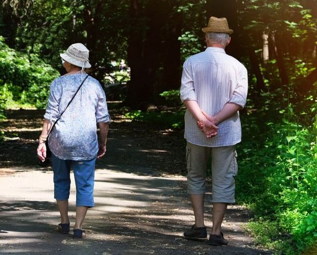 Pareja mayor caminando por un sendero rodeado de plantas