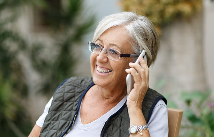 foto de mujer mayor sonriendo mientras habla por teléfono