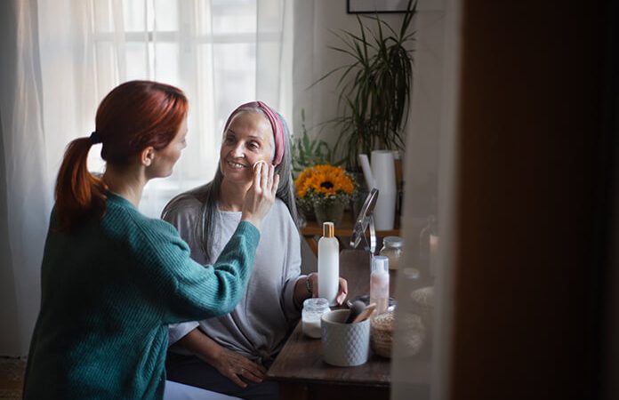 Cuidadora ayudando a adulta mayor con el maquillaje