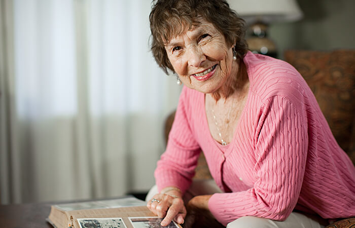 Foto de mujer mayor sonriendo mientras mira un album de fotos